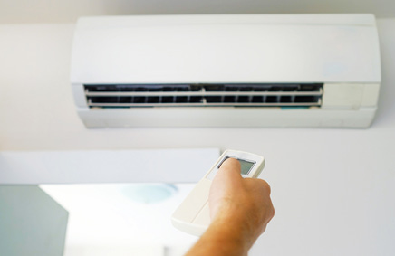 Person turning on their air conditioner with remote