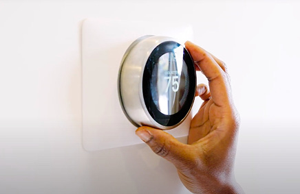 Person adjusting their thermostat