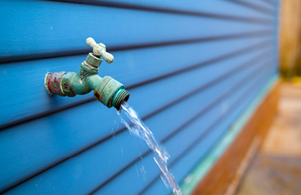 Image of water faucet on side of home