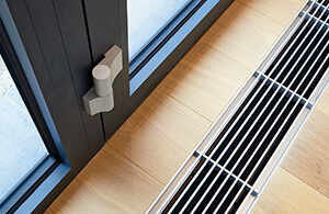 Hot air vents in the floor, next to a window
