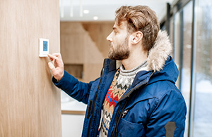 Man adjusting thermostat