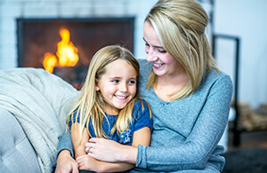 Mother and daughter by fireplace