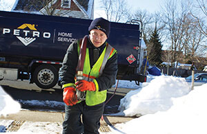 oil delivery driver attempting to reach a fill pipe through snow